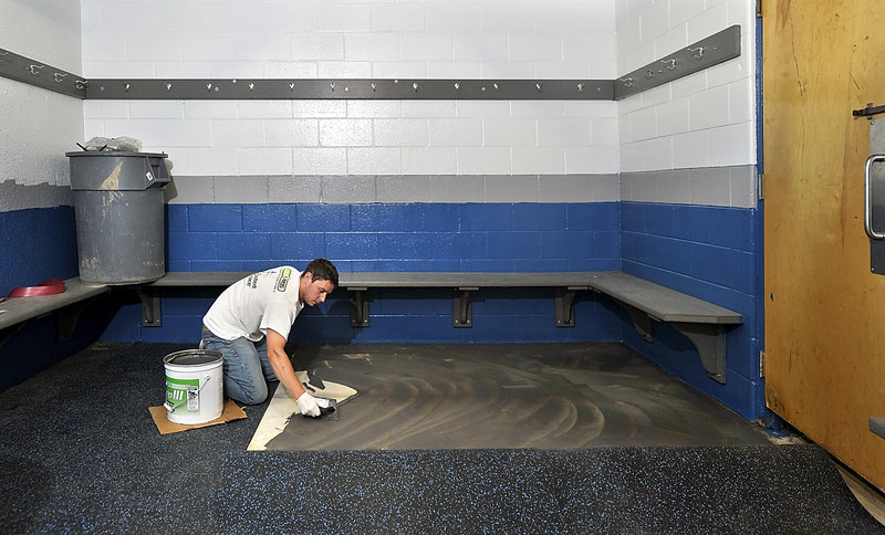 Anthony Reynolds, a Portland Ice Arena employee, spreads glue for new rubber matting in one of the locker rooms of the renovated facility. The arena reopens Tuesday after being closed since May.