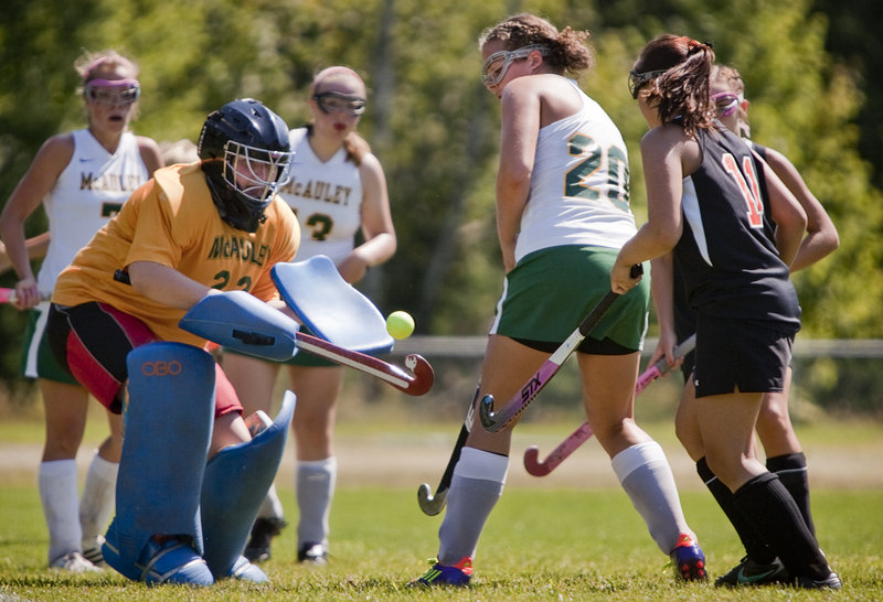 McAuley goalie Charlotte Murphy gets a handle on a loose field hockey ball in front of the net Saturday as teammate Hana Martinez, 20, and Biddeford’s Katie Letellier, right, look on. Biddeford came away with a 4-0 victory in Portland.