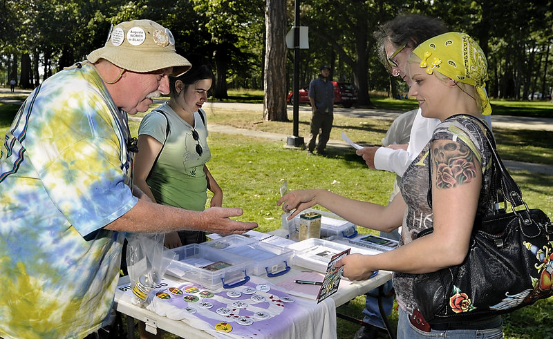 Roger Leisner, left, sells buttons to Lisa Beaudreau of Augusta at the Atlantic CannaFEST at Deering Oaks in Portland on Saturday. Leisner and Hillary Lister, second from left, are members of Medical Marijuana Caregivers of Maine and promote the use of medical marijuana for people who can benefit from it.