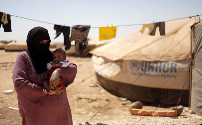 Refugee Omm Ahmed of Daraa, Syria, carries her newly born infant near her tent at Zaatari Refugee Camp in Mafraq, Jordan, on Sunday. UNICEF put the death toll from the Syrian civil war at 1,600 for last week alone.
