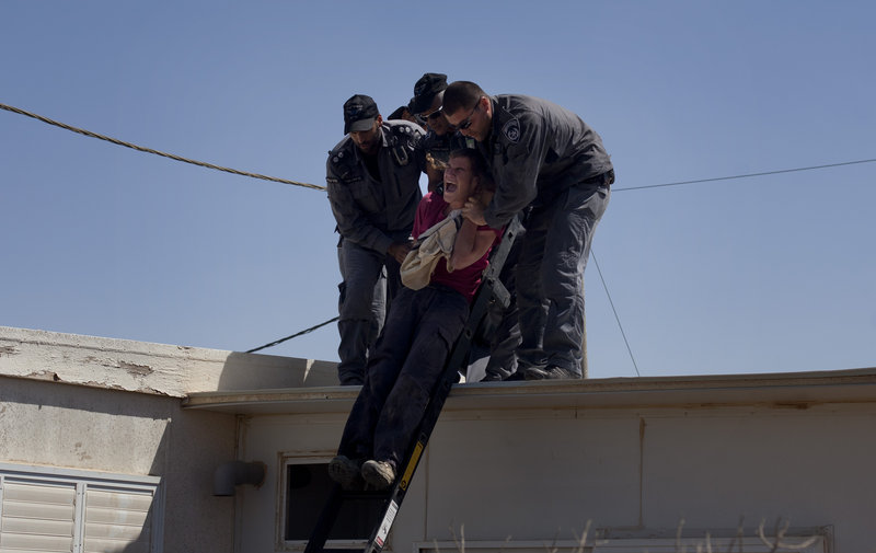 Israeli police officers evacuate a Jewish settler from the roof of a structure in the unauthorized West Bank Jewish settlement of Migron on Sunday. The court-ordered evacuation of Migron culminates years of legal wrangling.