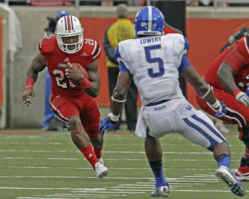 Jeremy Wright of Louisville tries to get past Kentucky’s Ashely Lowery during Sunday’s game at Louisville, Ky. Wright rushed for three touchdowns in a 32-14 victory.