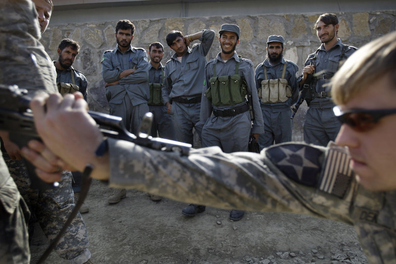 Afghan national policemen look on in 2009 as a U.S. soldier helps train the police on how to apprehend a gunman. The U.S. is reviewing its training program, and making changes, as 45 coalition troops have been killed by insider attacks this year.