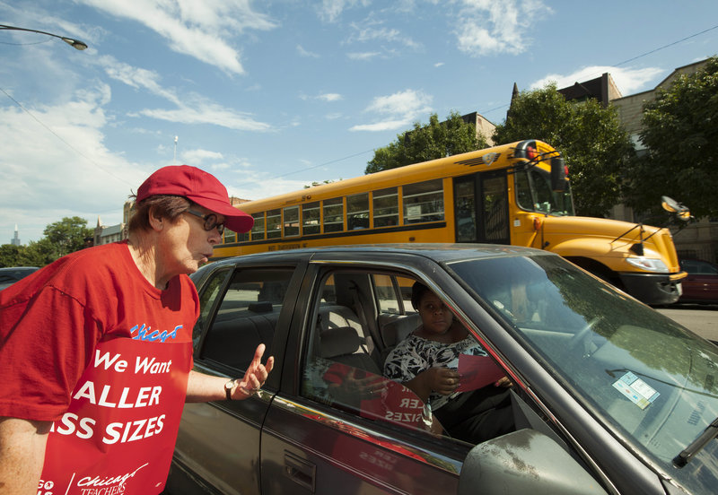 A member of the Chicago Teachers Union asks a parent for support in ongoing contract talks with the Board of Education, during an informational picket last month outside Willa Cather Elementary School in Chicago. The city’s teachers and support staff are prepared to strike next Monday.