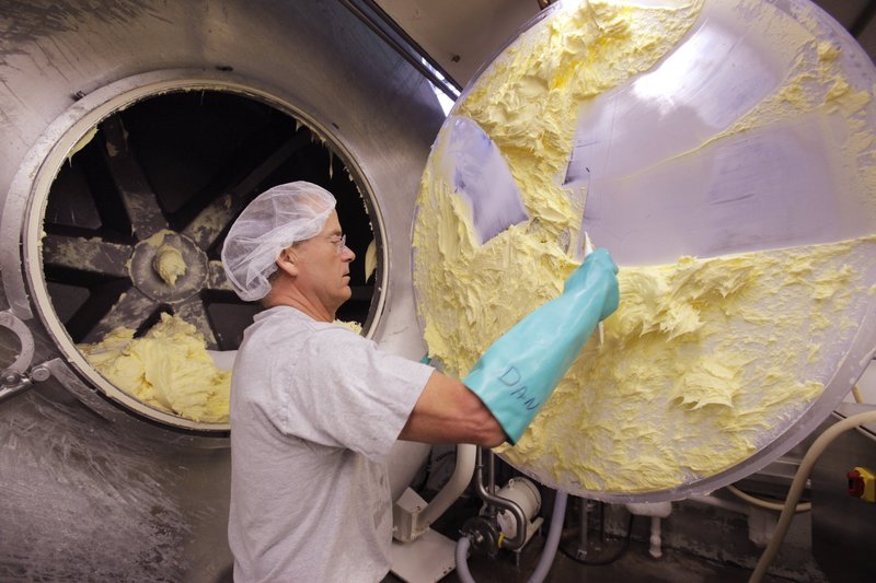 Dan Patry scrapes butter off a mixer door at Kate’s Homemade Butter. The creamery’s growth has led to complaints by its neighbors.