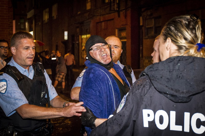 Police arrest a man outside the Parti Quebecois victory rally in Montreal on Wednesday after a masked gunman wearing a blue bathrobe opened fire, killing one person and wounding another.