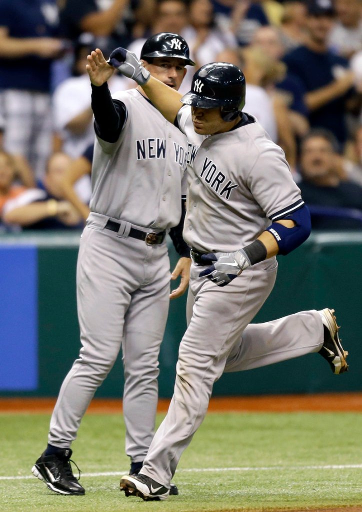 The Yankees’ Russell Martin, right, high-fives third-base coach Rob Thomson after his sixth-inning homer in a 6-4 win Wednesday over the Tampa Bay Rays.