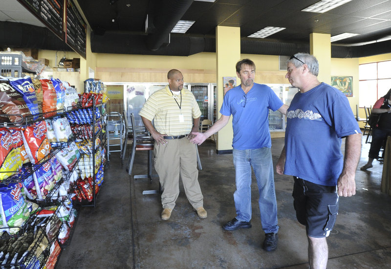 Tom Howard, center, owner of JP Thornton’s, talks with South Portland health inspector Derrick Stephens, left, and state health inspector Scott Davis about reopening his business Friday after a water main break caused heavy damage to his business and several others.