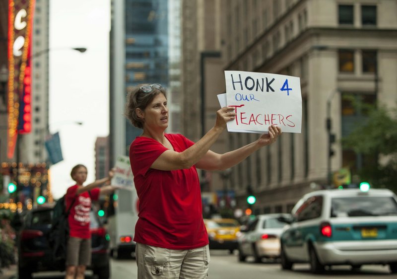 Members of the community group Parents 4 Teachers display pro-teacher posters outside City Hall on Friday in Chicago. Teachers have threatened to strike Monday.