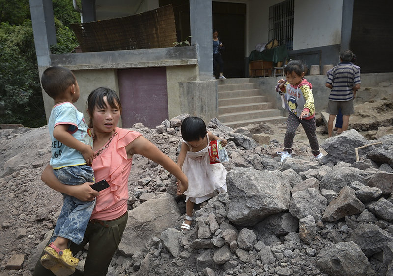 A woman and children flee earthquake damage in Luozehe township in hardest-hit Yiliang County in southwest China’s Yunnan province Saturday. Two quakes hit Friday.