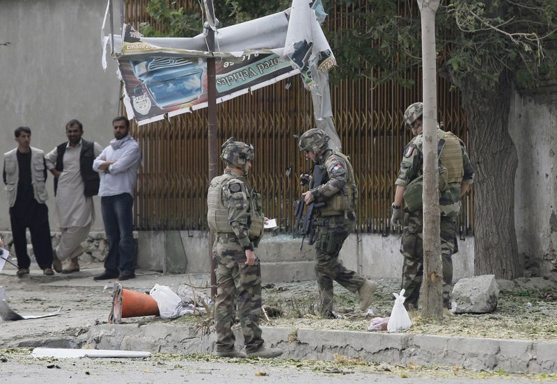 French soldiers, who are part of NATO forces, investigate the scene of a suicide attack Saturday in Kabul, Afghanistan. Police estimated the bomber to be about 14 years old.