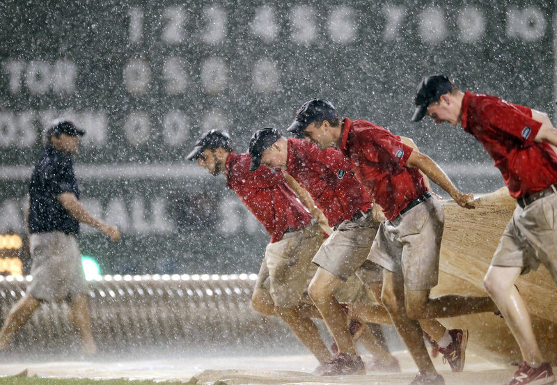 Members of the Fenway Park grounds crew pull the tarp onto the field during one of the two rain delays Saturday night. The Red Sox lost to Toronto, 9-2.