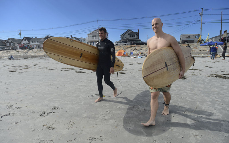 Ben Many of Portland, left, and Lloyd Hall of Biddeford make their way to the ocean carrying Grain Surfboards during the second annual Surf Re-Evolution festival at Long Sands Beach in York on Sunday.