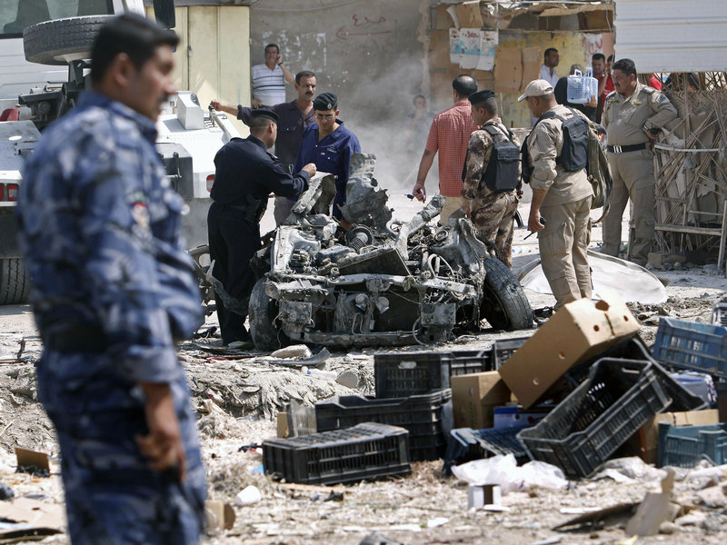 Security forces inspect the scene of a car bomb attack in Basra, Iraq, one of at least 13 cities that suffered bombings or shootings Sunday. The worst violence was in the capital, where bombs pounded a half-dozen neighborhoods much of the day.