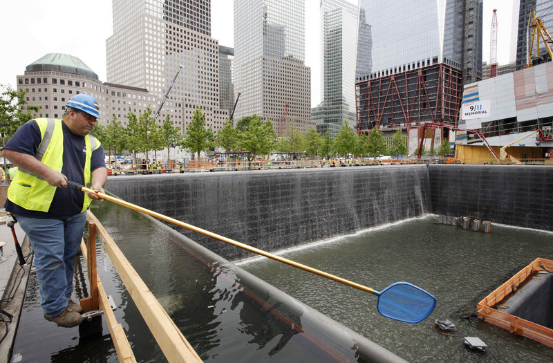 Anthony St. Jeanos uses a net to skim debris from the water during a test of the waterfalls at the National Sept. 11 Memorial and Museum at the World Trade Center site in New York. The site may not be complete until at least 2014.