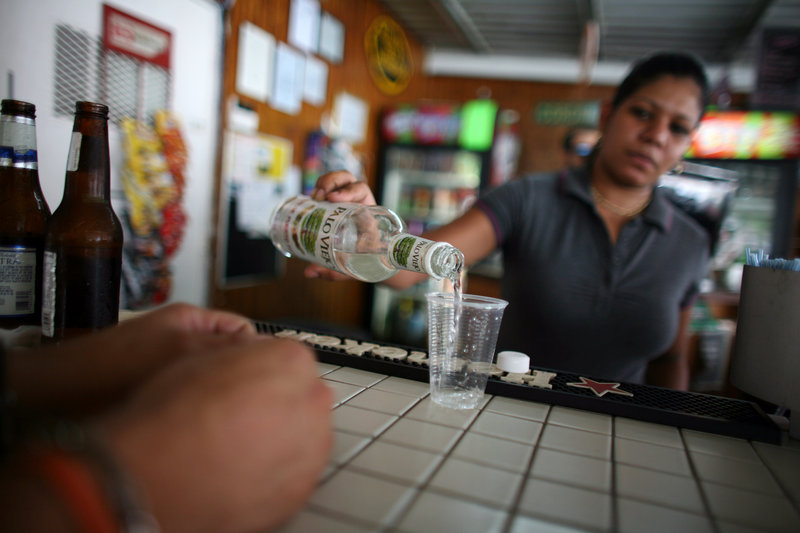 A bartender fills a glass with rum at a bar in San Juan, Puerto Rico. Small producers in countries such as Antigua, Guyana and Jamaica complain they are being pinched by unfair trade and marketing advantages for global beverage corporations operating in U.S. territories.