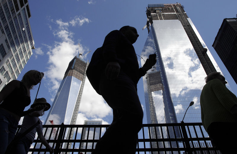 Visitors to the National September 11 Memorial walk Monday below the rising towers of 1 World Trade Center, left, and 4 World Trade Center. Tuesday will mark the 11th anniversary of the attacks of Sept. 11, 2001.