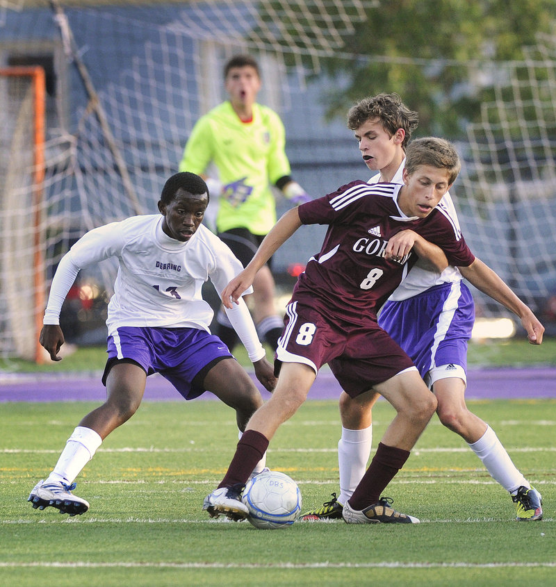 Jonathan Bujambi, left, and Jimmy Fasulo of Deering try to take the ball away from Gorham’s Spence Cowand.