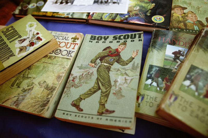 Boy Scout handbooks from over the years are shown at a campsite. Readers debate the value of proposals to change the Scouts’ policies on the involvement of gays.