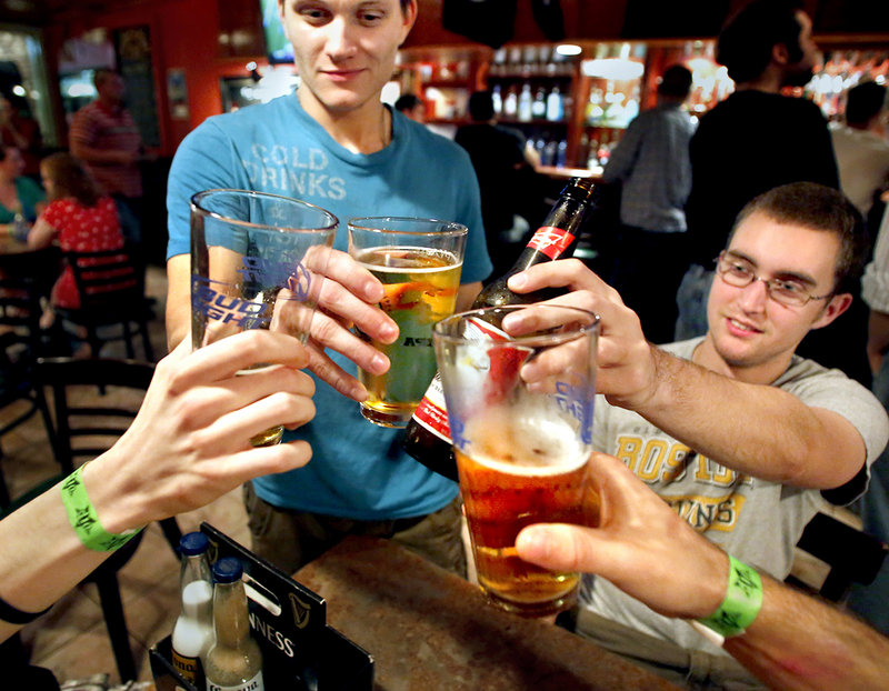 Joseph Miller, a UMaine senior from Topsham, left, and fellow senior Andy Bepuain of Bangor toast with friends at the Bear Brew Pub in Orono on a recent Friday night. “I think people party almost out of necessity,” Miller said.