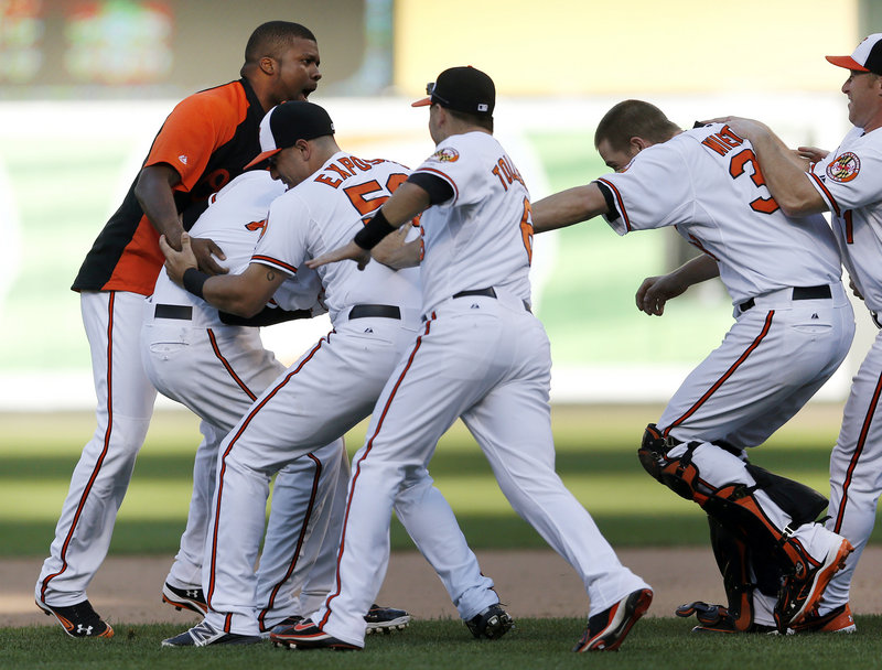 The Baltimore Orioles continue to stay hot, as they mob Manny Machado, second from left, after his 14th-inning single beat the Tampa Bay Rays 3-2 at Baltimore on Thursday.