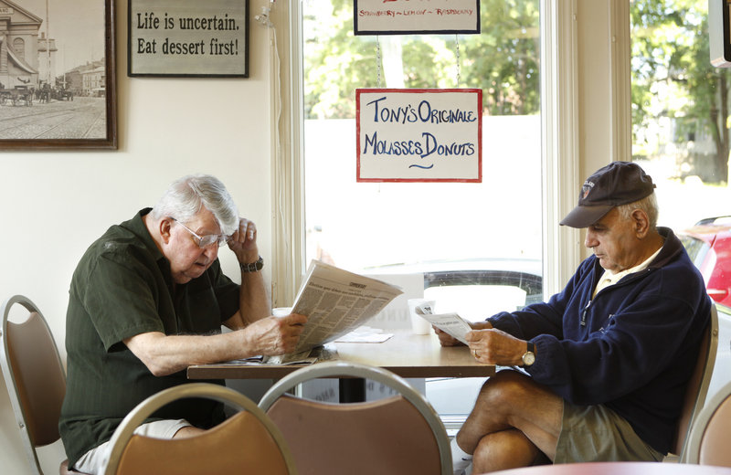 Herb Ledue, left, and Arthur Lekousi read newspapers at Tony’s Donuts in Portland. They visit Tony’s three or four times a week for a plain doughnut or a cruller and coffee. Americans eat an average of nine doughnuts a year – a figure Tony’s customers scoff at.