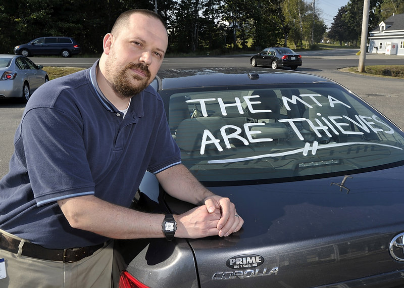 Joe Thibeault, a commuter from Saco, displays a statement on his car’s back window expressing his anger over the new toll system that goes into effect Nov. 1. “I was shocked,” Thibeault said in response to the increase he faces.