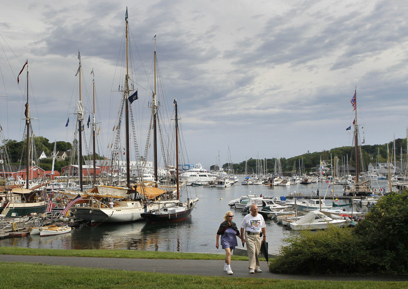 A couple stroll through a park by the harbor in Camden in August. Camden is often cited in lists of best retirement places for people interested in cooler climates.