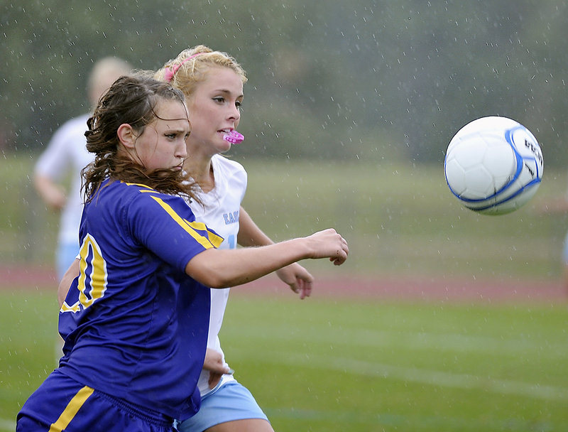 Eden Monsen of Cheverus, foreground, races Melissa Morton of Windham for a loose ball in the rain Tuesday during unbeaten Windham’s 3-1 victory in girls’ soccer.