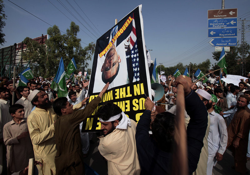 Protesters strike a poster bearing a portrait of U.S. President Barack Obama near the U.S. consulate in Peshawar, Pakistan, on Tuesday. Hundreds of protesters broke through a barricade outside the consulate, sparking clashes with police that left several wounded on both sides, police said.