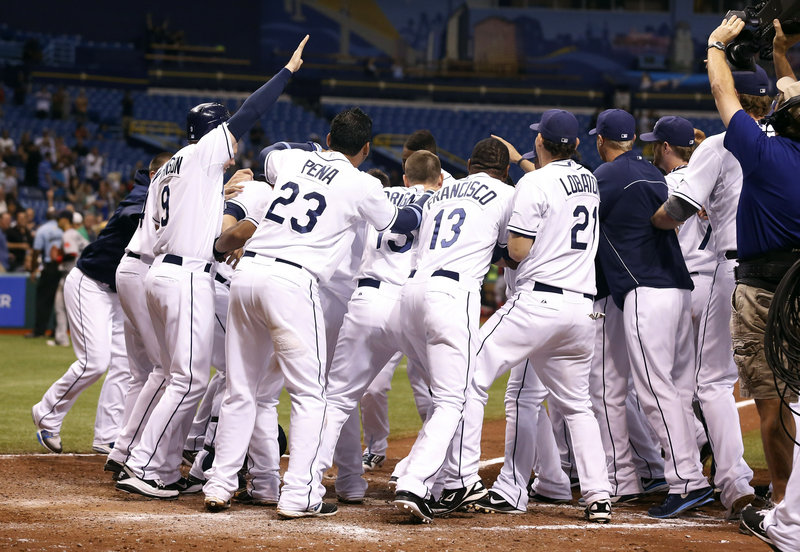 B.J. Upton of the Rays gets mobbed by teammates after hitting a winning three-run homer to cap a six-run ninth inning Thursday night at St. Petersburg, Fla. Boston had a 4-1 lead entering the bottom of the ninth.