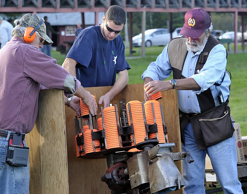 Jack Studley, left, Nick Wright and Ross MacKinnon load the trap-shooting machine with new disks at the Lincoln County Rifle Club.