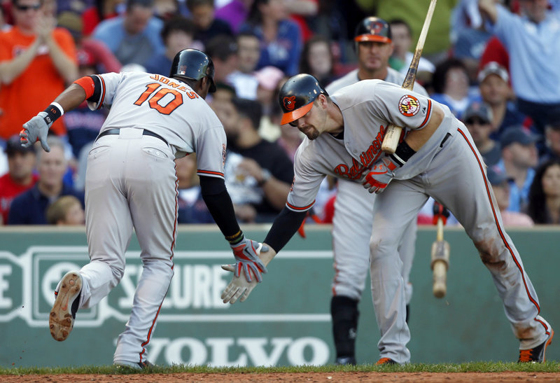 Adam Jones, left, is welcomed by Matt Weiters of the Baltimore Orioles after hitting a home run in the seventh inning Saturday that helped beat the Boston Red Sox 9-6 in 12 innings.