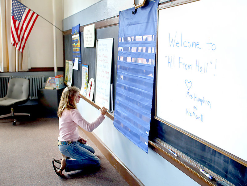 Erin Humphrey, a first- and second-grade teacher at Hall Elementary School, writes a message welcoming students back to school in a classroom at Cathedral School in Portland on Monday afternoon, Sept. 24, 2012.