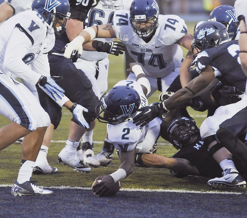 Kevin Monangi, who gained 192 yards on 30 carries for Villanova, dives into the end zone Saturday, past Kari Al-Mateen of the University of Maine, during Villanova’s 35-14 victory in Orono that dropped the Black Bears to 1-3.