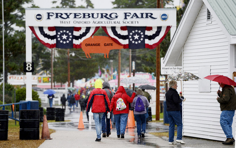 Fairgoers break out umbrellas as they make their way into the Fryeburg Fair on Sunday.