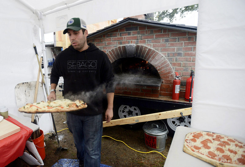 Ryan Carey of Pizza Pie on the Fly takes a steaming hot pizza from the brick oven to serve at the Fryeburg Fair on Sunday.