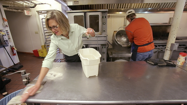 Democrat Cynthia Dill wipes down a kitchen counter while volunteering at the Preble Street center in Portland.
