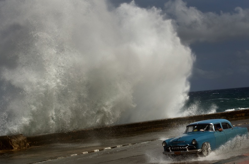 A driver maneuvers his classic American car along a wet road as a wave crashes against the Malecon in Havana on Thursday as Hurricane Sandy blasted across eastern Cuba.