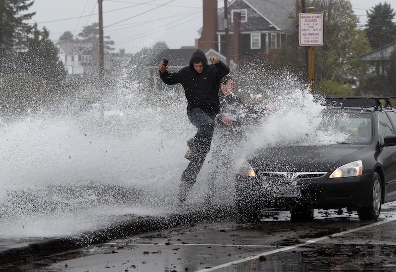 Caleb Lavoie, 17, of Dayton, Maine, front, and Curtis Huard, 16, of Arundel, Maine, leap out of the way as a large wave crashes over a seawall on the Atlantic Ocean during the early stages of Hurricane Sandy on Monday.