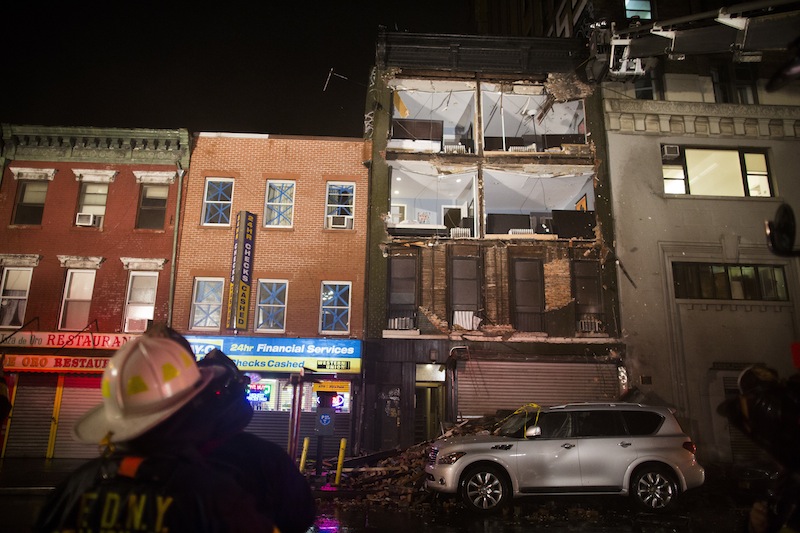 Firefighters look up at the facade of a four-story building on 14th Street and 8th Avenue that collapsed onto the sidewalk Monday, Oct. 29, 2012, in New York. Hurricane Sandy bore down on the Eastern Seaboard's largest cities Monday, forcing the shutdown of mass transit, schools and financial markets, sending coastal residents fleeing, and threatening a dangerous mix of high winds, soaking rain and a surging wall of water up to 11 feet tall. (AP Photo/ John Minchillo)