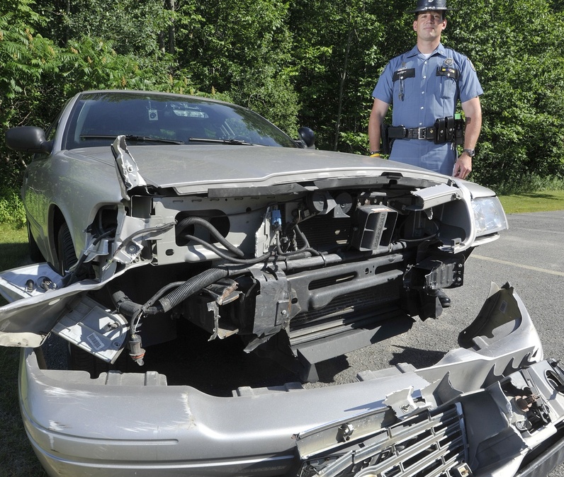 Maine State Police Trooper Douglas Cropper stands beside the police cruiser he used to stop an elderly driver who was heading north in the southbound lane of Interstate 295 on June 29.