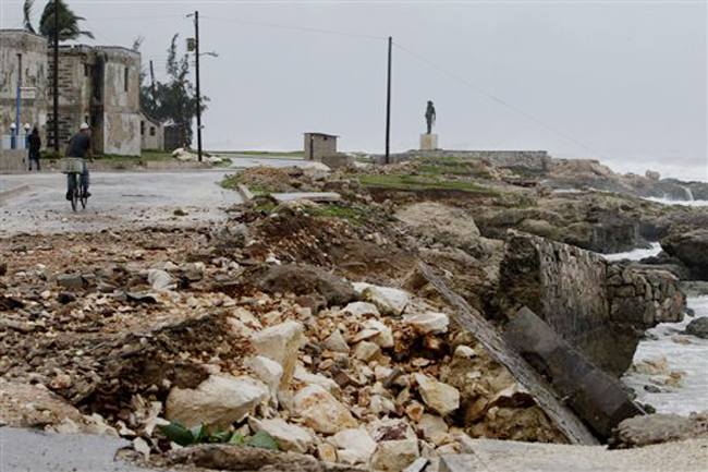 The sea wall and a road is partially damaged after the passing of Hurricane Sandy in Gibara, Cuba, Thursday, Oct. 25, 2012. Hurricane Sandy blasted across eastern Cuba on Thursday as a potent Category 2 storm and headed for the Bahamas after causing at least two deaths in the Caribbean. (AP Photo/Franklin Reyes)