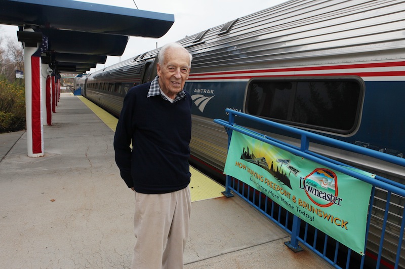 Nelson Soule, 91, poses next to the Amtrak Downeaster train Wednesday, Oct. 31, 2012 at the station in Portland, Maine. Soule will be aboard Amtrak's Downeaster on Thursday as the Boston-to-Portland service expands northward to Freeport and Brunswick for the first time in more than 50 years. (AP Photo/Joel Page)