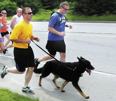 Waterville Police Officer Lincoln Ryder, far right, and Kennebec County Sheriff's Cpl. G.J. Neagle III, second from right, with Dracco, his police dog, lead a leg of the Special Olympics Torch Run through Winslow into Waterville on June 7, 2012.