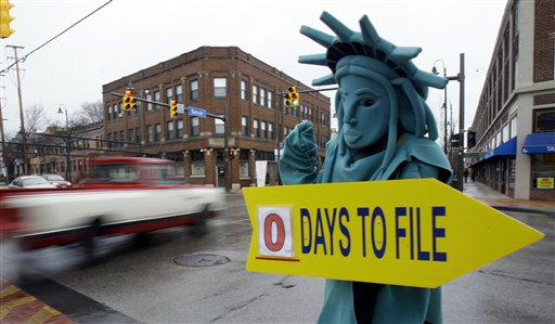 Max Martinez, dressed as the Statue of Liberty, tries to alert motorists on April 18, 2011, the final day to file taxes. A typical middle-income family could see its taxes go up by $2,000 in 2013 if lawmakers fail to renew a lengthy roster of tax cuts set to expire at the end of 2012. Should that crisis, calld the "fiscal cliff," be resolved, Americans can expect faster economic growth and lower unemployment, experts say.