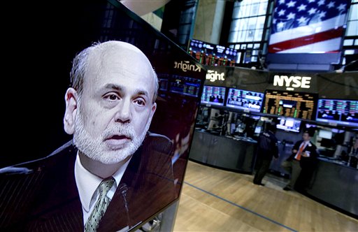 Federal Reserve Chairman Ben Bernanke appears on a television screen on the floor of the New York Stock Exchange in June. On Monday, Bernanke told the Economic Club of Indiana that the Fed needs to drive down borrowing rates because the economy isn’t growing fast enough to reduce high unemployment.