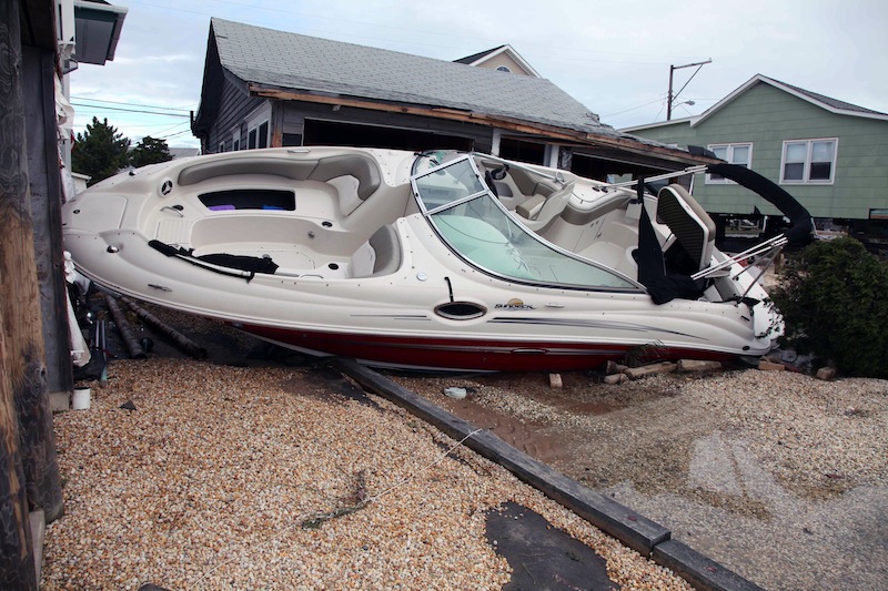 A boat rests up against a house in the wake of superstorm Sandy Wednesday Oct. 31, 2012 in Cedar Bonnet Island, NJ. Power is still out and residents who evacuated the island are still not being allowed back in. Sandy was being blamed for at least six deaths across the state of New Jersey plus power outages that at their peak Monday affected 2.7 million residential and commercial customers. (AP Photo/Robert Ray)