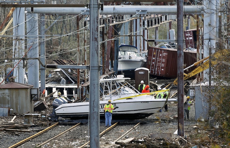 Workers try to clear boats and debris from the New Jersey Transit's Morgan draw bridge Wednesday, Oct. 31, 2012, in South Amboy, N.J., after Monday's storm surge from Sandy pushed boats and cargo containers onto the train tracks. New Jersey Transit's North Jersey Coast Line, which provides train service from the New Jersey shore towns to New York City, may experience prolonged disruption because of the extensive damage. (AP Photo/Mel Evans)