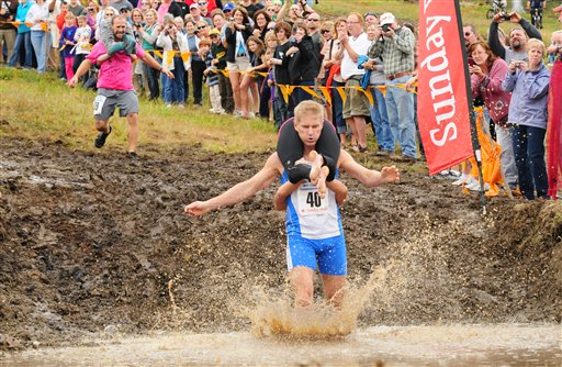 World Wife Carrying Champions Taisto Miettinen and Kristina Haapanen, from Helsinki, Finland, enter the water hazard just moments before second-place finishers Jesse Wall and Christine Arsenault of South Paris during the finals of the 2012 North American Wife Carrying Championship on Saturday at Sunday River in Newry, Maine. The Finnish duo took first place with a time of 52.58 seconds. "Against Taisto, we went in hand to hand, shoulder to shoulder and he got that big long leg in front of my stomach and I just couldn't quite get over it," said Wall of the first log hurdle on the course. "I got stuck there. We lost some time to him."